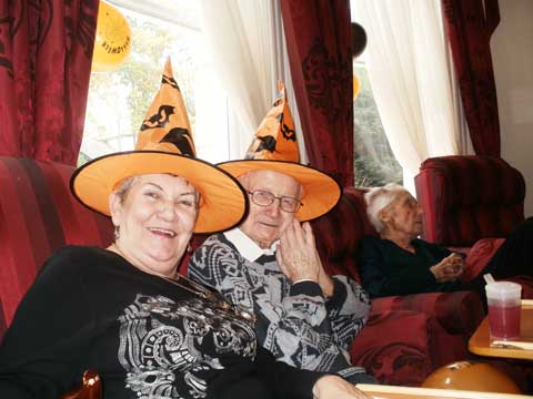 close-up of two residents in party hats smiling and enjoying the group party